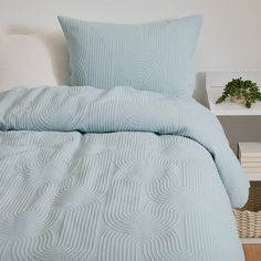 a bed with blue comforter and pillows on it next to a night stand in a bedroom