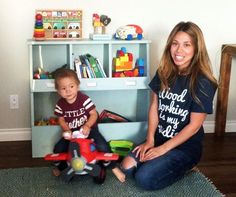 a woman sitting on the floor next to a little boy with a toy airplane in front of her