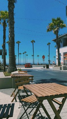 some tables and chairs on the side of the road with palm trees in the background