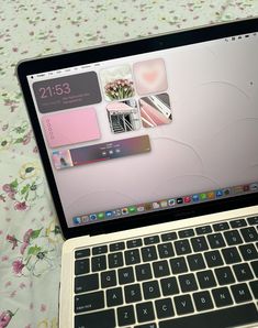 an open laptop computer sitting on top of a floral covered tablecloth with pink flowers