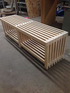 a wooden bench sitting on top of a floor next to a pile of plywood