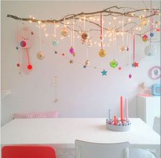 a white table topped with two red chairs next to a wall covered in christmas ornaments