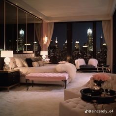 a bedroom with a view of the city lights at night and white fur rugs on the floor