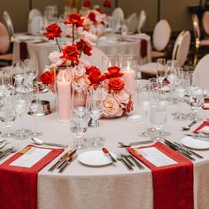 the table is set with silverware and red napkins, candles and flowers in vases