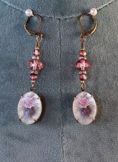 Beautiful and feminine antique gold earrings with 6x8mm translucent burgundy crystal beads, 3mm Czech glass raspberry beads, and 13mm x 18mm pendants with pink and burgundy roses on a white background with a matte finish. These earrings are 2.5" long and 13mm wide.  Free shipping in the USA! Your purchase will be well packaged for shipping and arrive gift packaged. Will ship USPS First Class next day after payment, excluding Sundays and holidays. Includes tracking. Returns: If you are not happy with your purchase, please return within 14 days of purchase for a full refund minus shipping charges. Pink Victorian Earrings For Gift, Victorian Style Pink Earrings For Gift, Antique Pink Earrings As Gift, Antique Pink Earrings Gift, Antique Pink Earrings For Gift, Vintage Rose Gold Round Earrings, Handmade Vintage Rose Gold Earrings, Vintage Czech Glass Matching Earrings, Elegant Earrings With French Hook And Czech Glass