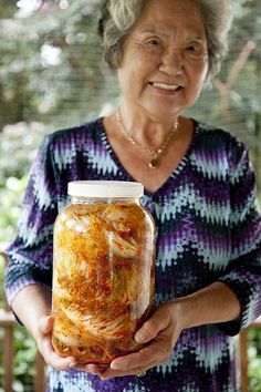 an older woman holding a jar filled with food