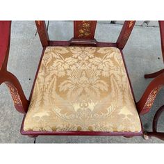 an old chair is sitting on the sidewalk next to some red chairs and a table