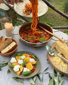 a table topped with plates of food and bowls of pasta on top of a white table cloth