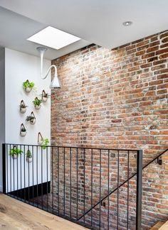 a brick wall with potted plants on it and a metal railing in the foreground