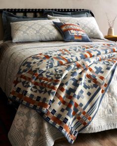 a bed with blue, orange and white bedspread on it in a bedroom