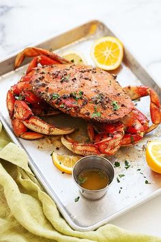 a crab on a tray with lemons and sauce