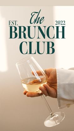 a person holding a wine glass with the brunch club logo in front of it