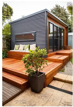 a small backyard with wooden steps leading up to the decking area and a potted plant