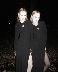 two women dressed in black standing next to each other with white makeup on their faces