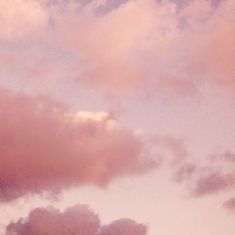 an airplane is flying in the sky with pink clouds