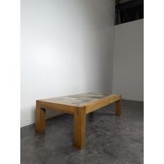 a wooden table sitting on top of a cement floor next to a white walled wall