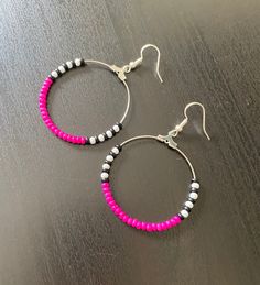 two pairs of pink and white beaded hoop earrings on a wooden table with silver earwires