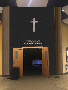 an empty church entrance with a cross on the wall and worship center sign above it