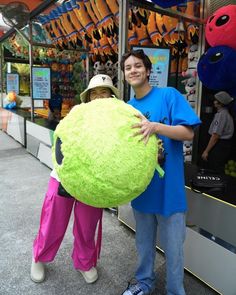 two people standing next to each other in front of a store with stuffed animals on display