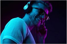 a man wearing headphones and listening to music in the dark with neon lights behind him