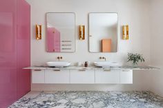 a bathroom with two sinks and mirrors on the wall next to each other in front of a pink cabinet