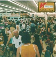 many people are shopping in a store with signs above them that read, walmart