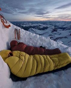 a man sleeping on top of a snow covered mountain