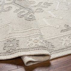 a close up of a rug on the ground with wood flooring in the background