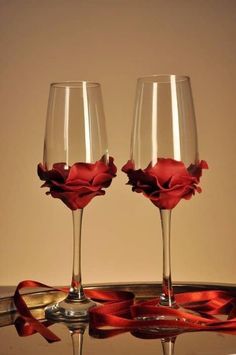 two wine glasses sitting on top of a table with red ribbon around the rims