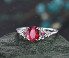 a close up view of a ring with a red stone in the center on a rock