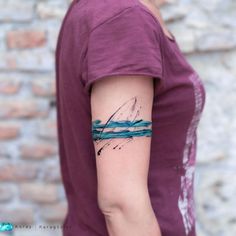 a woman's arm with a blue and black ink painting on the left side of her arm