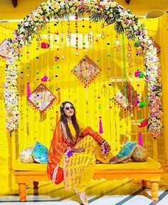 a woman sitting on top of a bench in front of a yellow stage with decorations