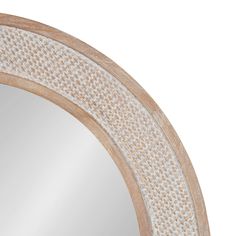 an oval mirror is shown against a white background and has woven trim around the edge