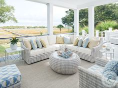 a living room filled with lots of furniture under a covered porch next to a large window