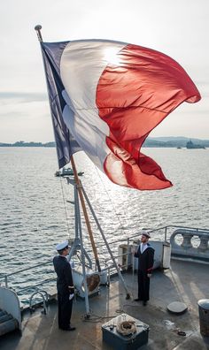 two men standing on the deck of a boat with an american flag flying from it