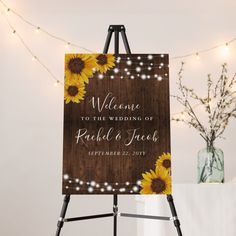 a wooden sign with sunflowers on it in front of lights and string lights