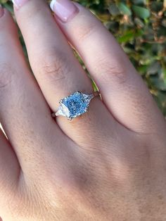 a woman's hand with a blue diamond ring on it