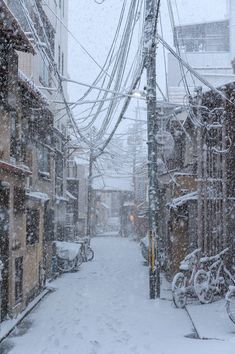 a snowy street with lots of buildings and bicycles parked on the side walk, all covered in snow