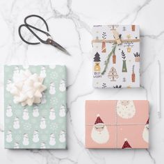 wrapping presents on a marble table with scissors and other holiday decorating items around them