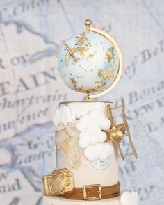 a three tiered cake with an airplane and globe on top, sitting in front of a map