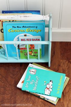 two books are sitting on the floor next to a toy book rack with children's books in it