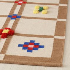 an area rug with different colored squares on it and pom poms scattered around