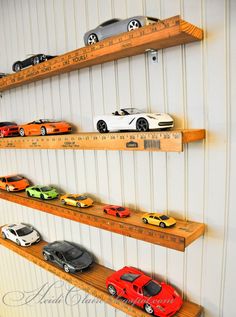 there are many toy cars lined up on the shelf in front of the rulers