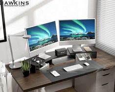 two computer monitors sitting on top of a wooden desk