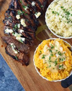 some meat and mashed potatoes are on a cutting board next to other food items