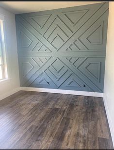 an empty room with wood flooring and blue painted panels on the wall behind it