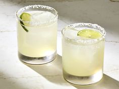 two margaritas sitting next to each other on top of a white marble countertop