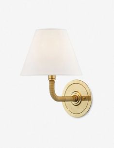 a wall light with a white shade on the side and a gold finish to it