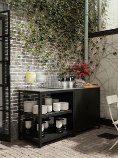 a table with plates and cups on it in front of a brick wall