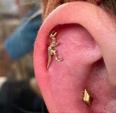 a close up of a person's ear with a small gold lizard on it